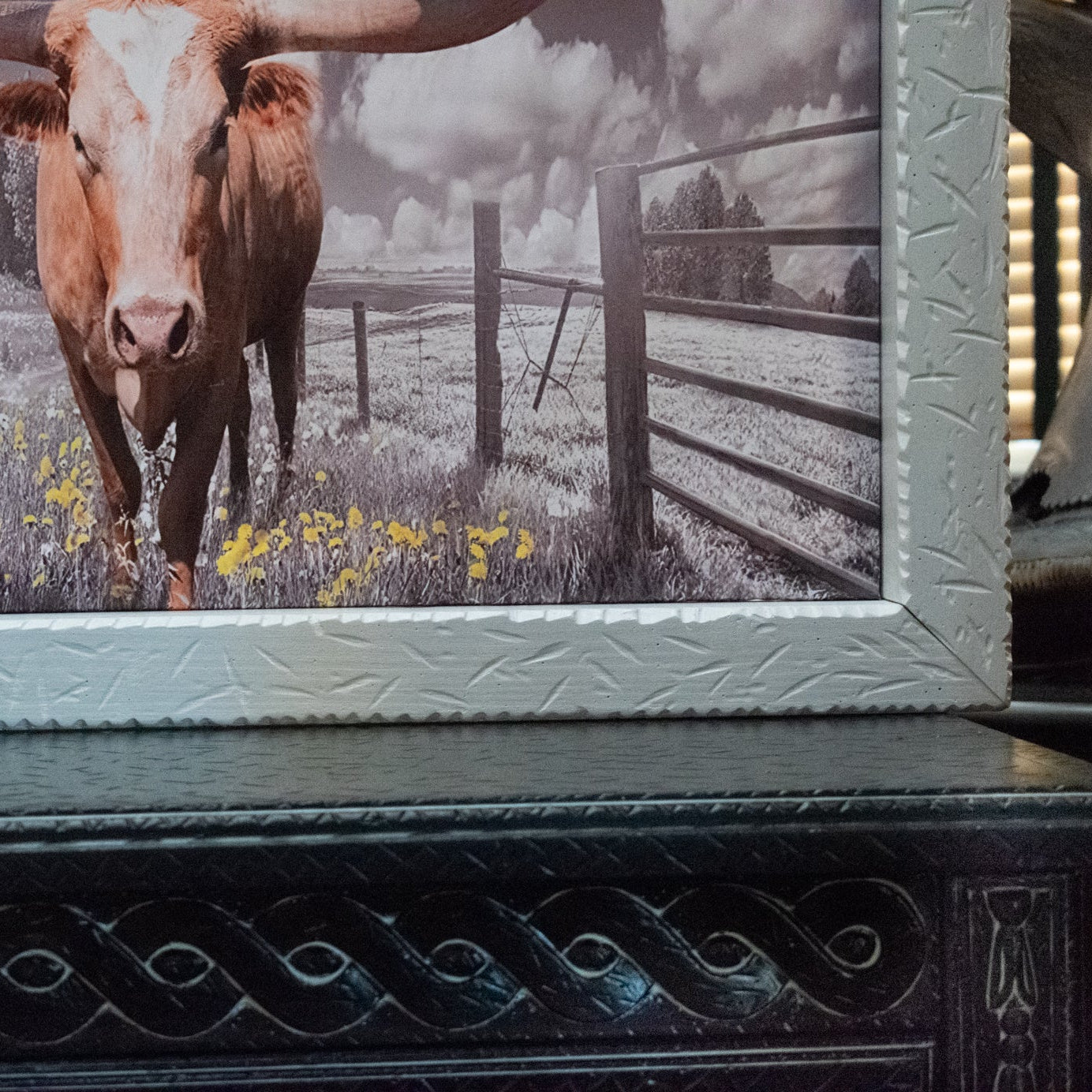 Framed picture of a cow in a field with a decorative frame.