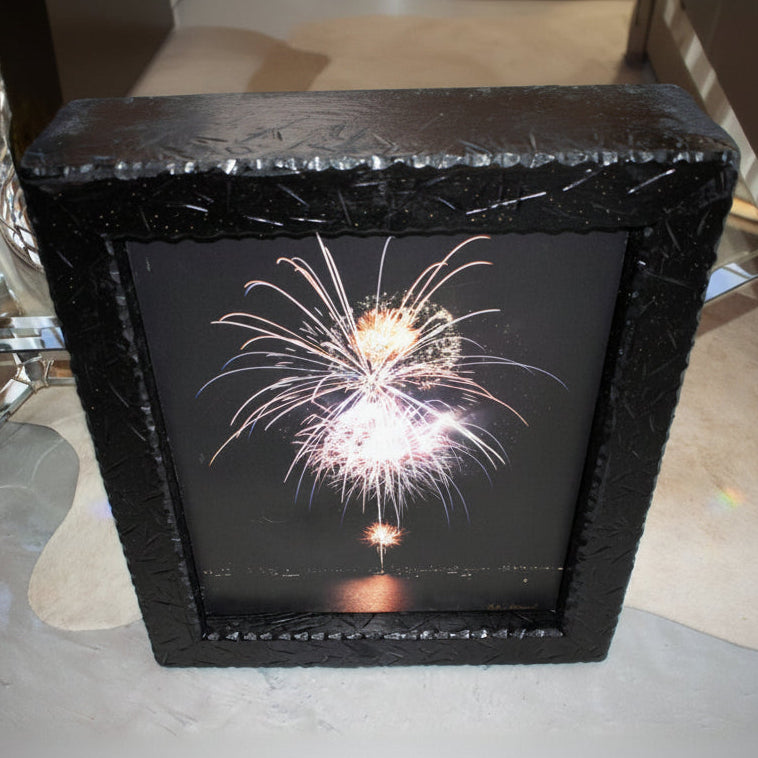 John Hummel framed fireworks canvas print featuring colorful nighttime fireworks reflected over water in rustic black textured wood frame