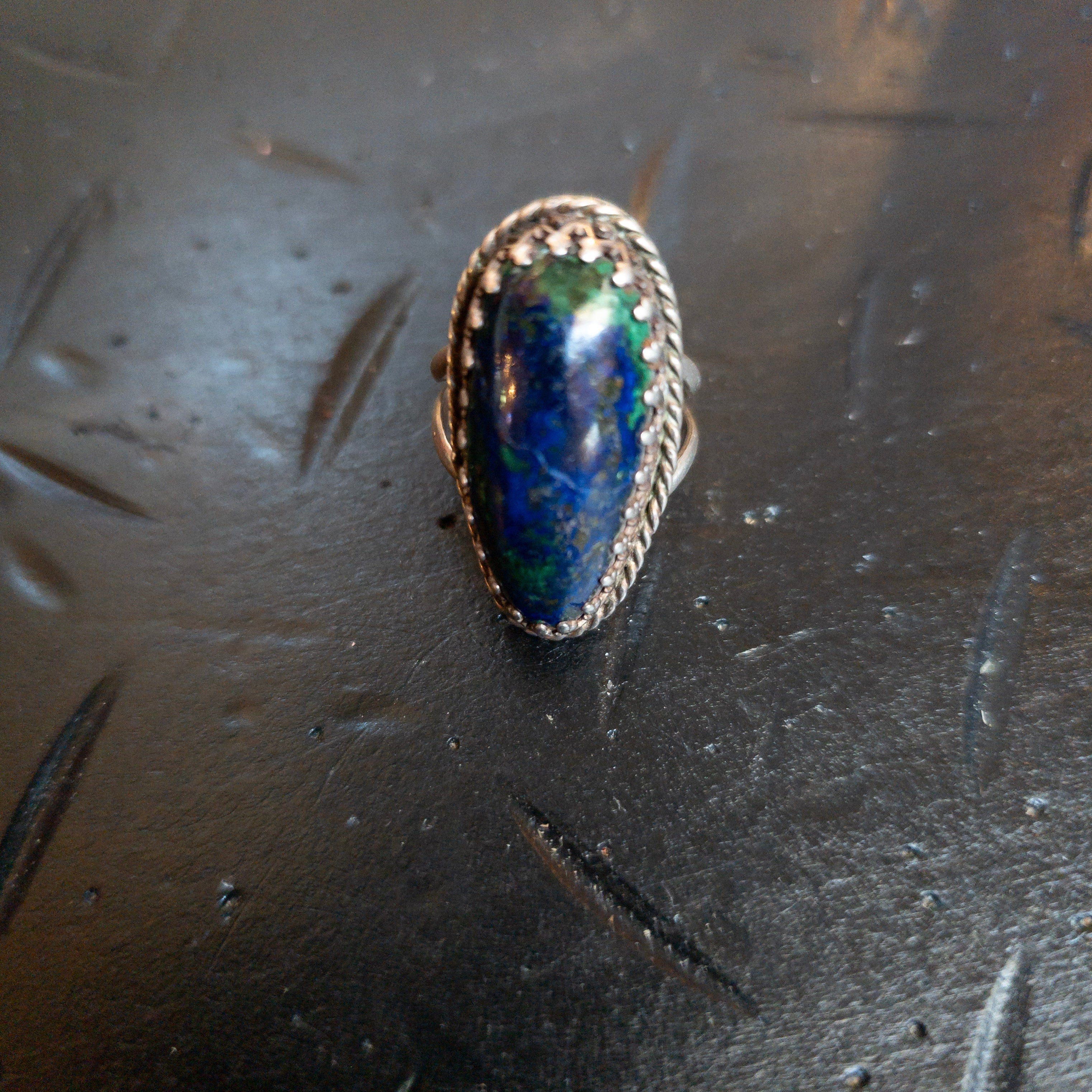 Vintage size 6 Southwestern-style fashion ring featuring an elongated oval blue and green cabochon set in an ornate rope-style bezel with a split shank base metal setting.