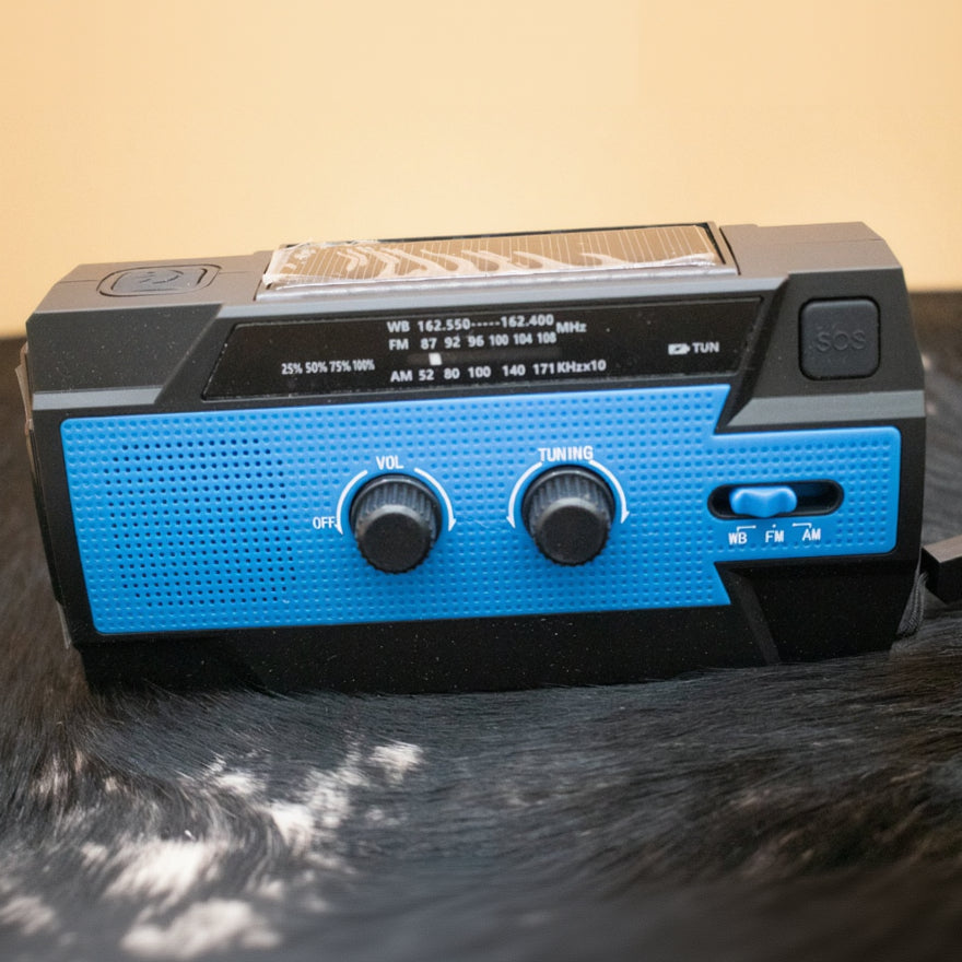 A black and blue multi-purpose emergency crank radio with solar panel and USB charger