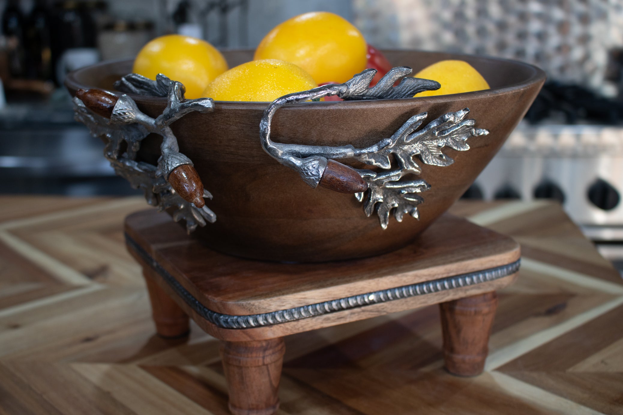 large handcrafted wooden bowl with decorative silver acorn and oak leaf branch handles filled with fruit rustic harvest collection decor