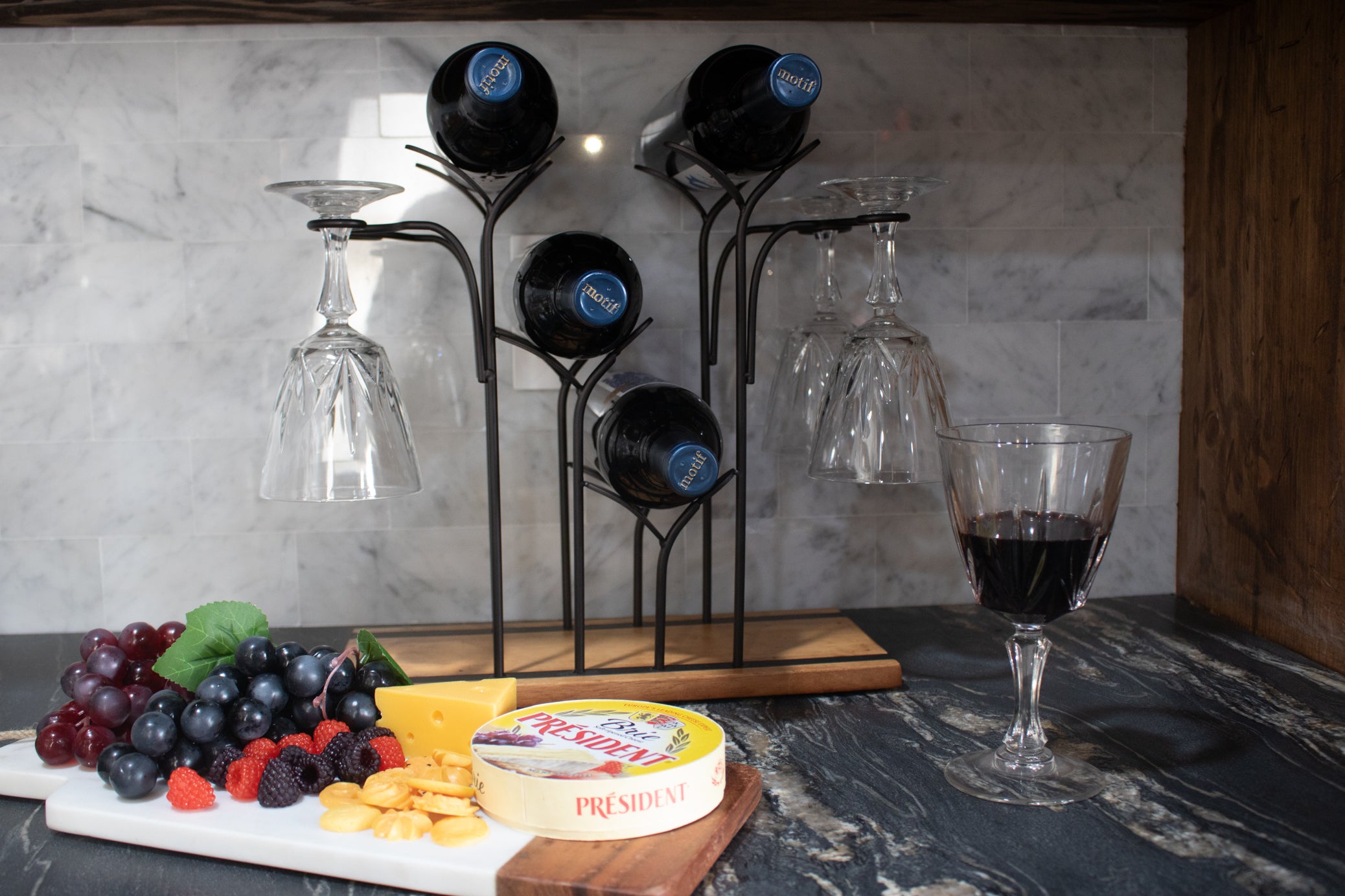black metal wine bottle and stemware display rack with rustic wood base holding wine bottles and hanging wine glasses