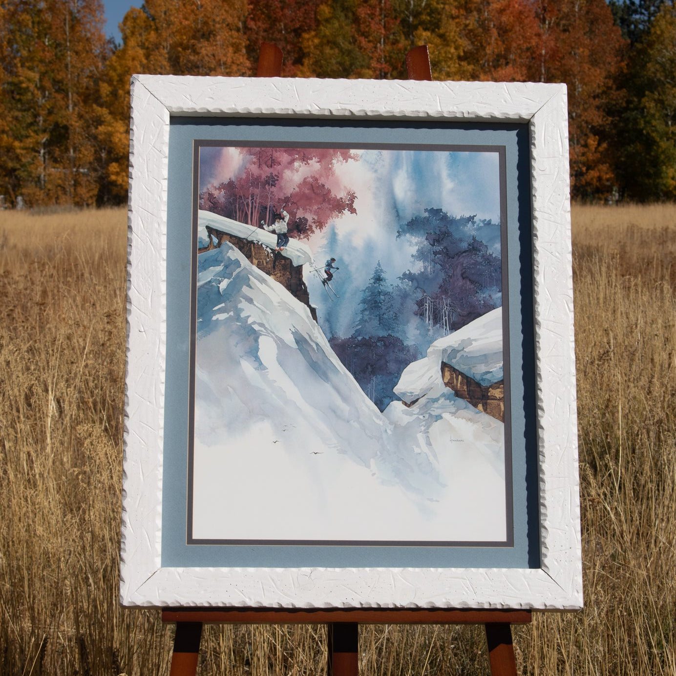 Framed winter ski landscape painting by Michael Atkinson with skiers on snowy mountain slope