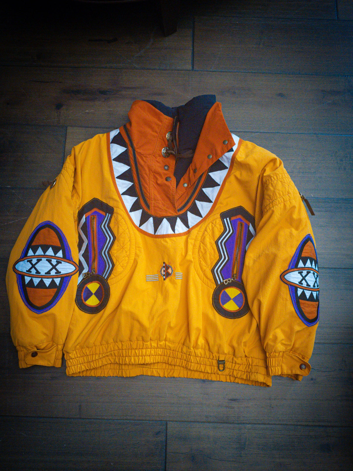 Front of the Bogner Goan Thylmann jacket laid flat showing sawtooth yoke, zigzag zip pockets and sleeve shield patches