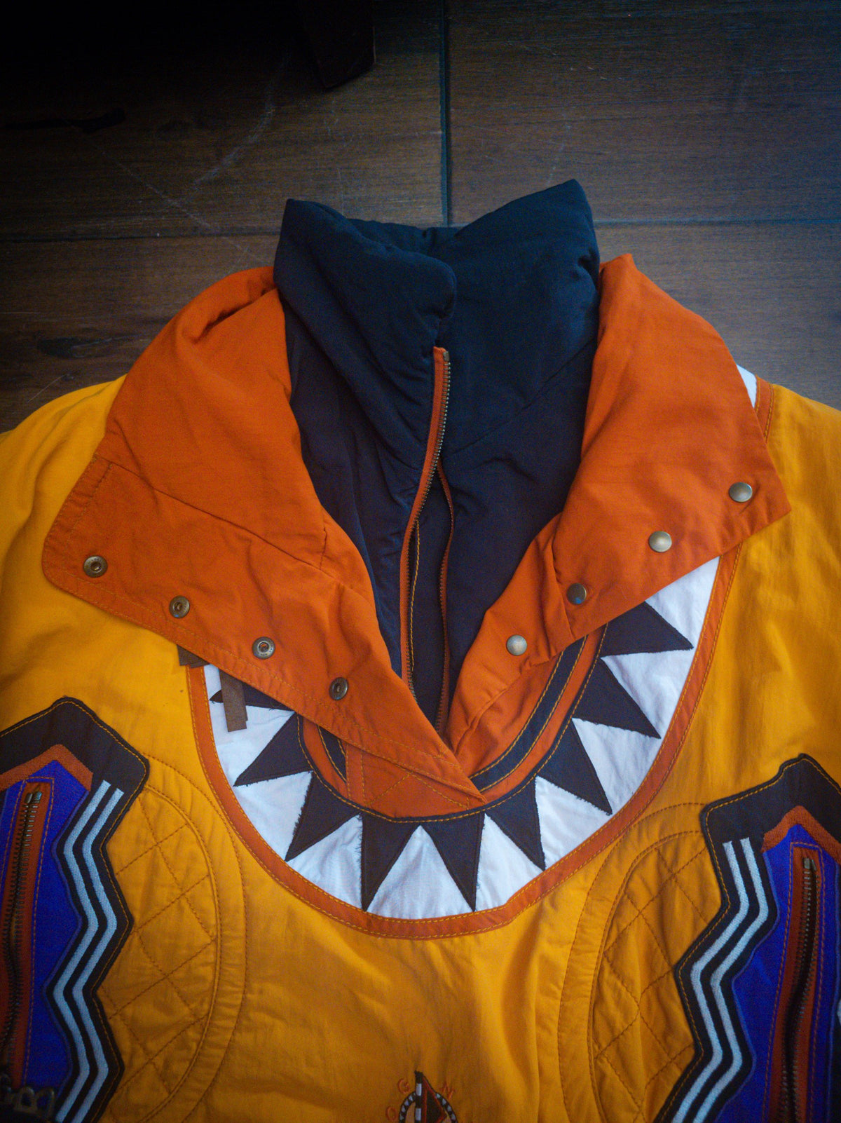 Close-up of the burnt orange snap collar, navy zip neck and sawtooth appliqué yoke