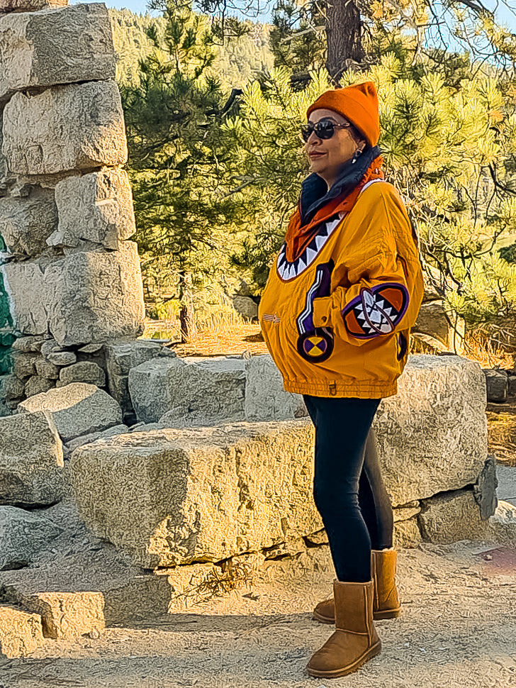 Side view of the Bogner ski jacket worn with an orange beanie and sunglasses in the mountains