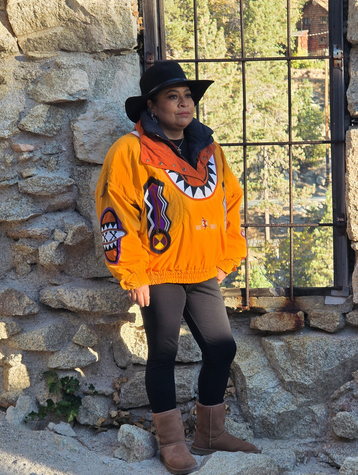 Vintage 90s Bogner Goan Thylmann ski jacket in marigold worn with a black hat against a stone wall
