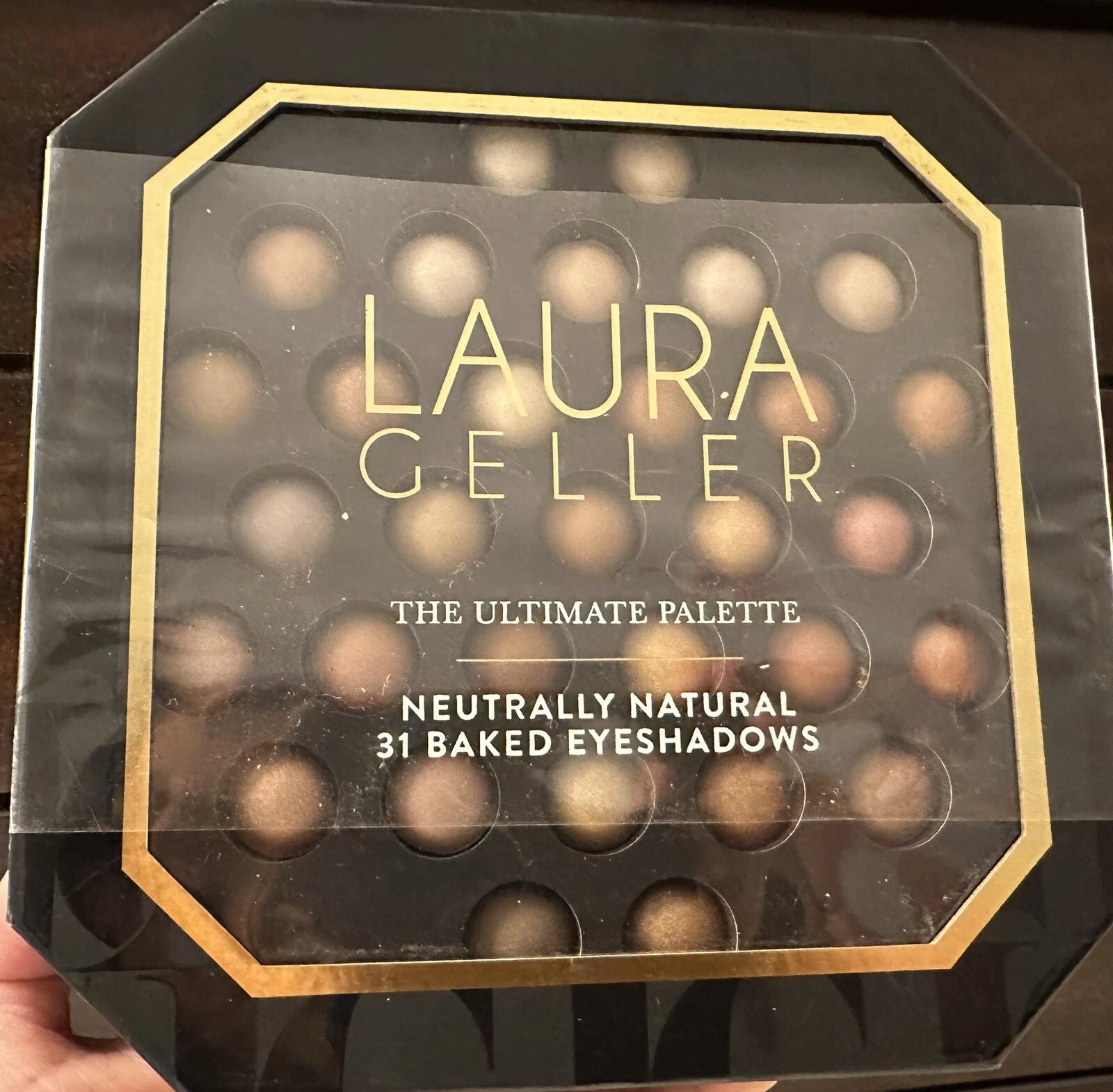 Laura Geller eyeshadow palette with gold accents on a dark background