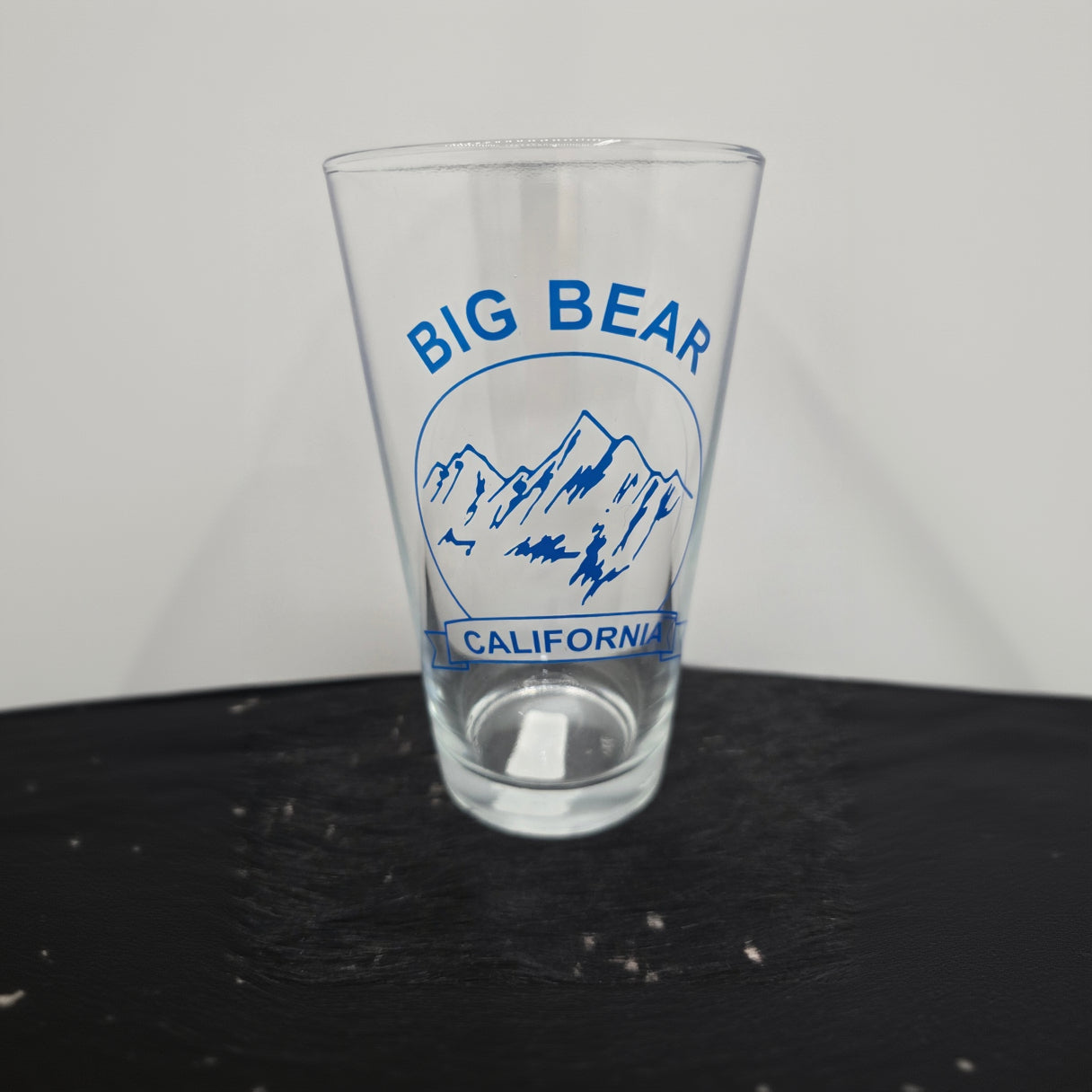 assorted Big Bear California themed pint beer glasses featuring bear paw mountain and forest logo designs for rustic cabin and lodge drinkware