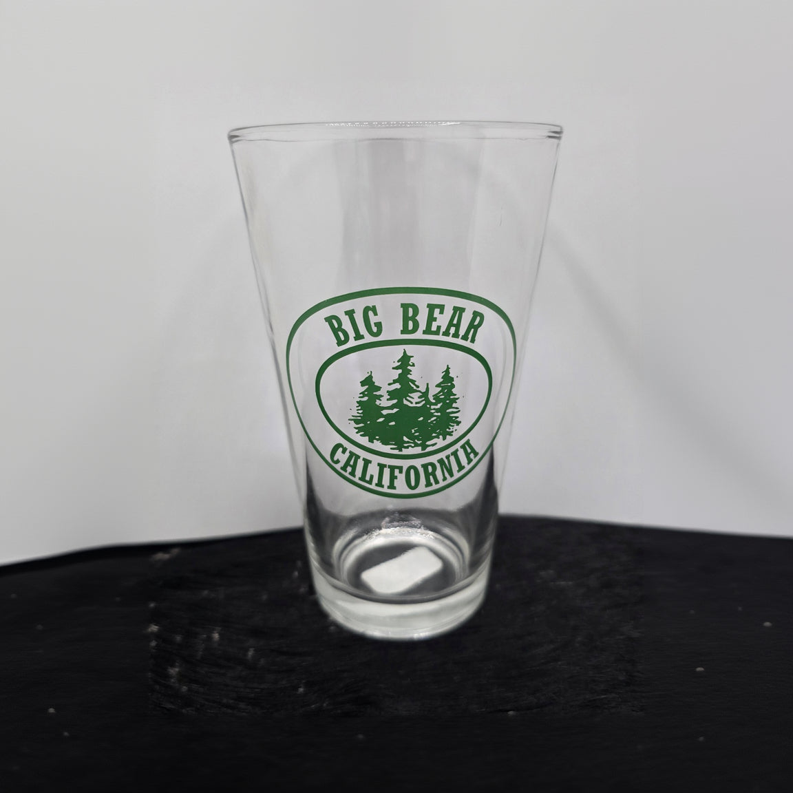 assorted Big Bear California themed pint beer glasses featuring bear paw mountain and forest logo designs for rustic cabin and lodge drinkware