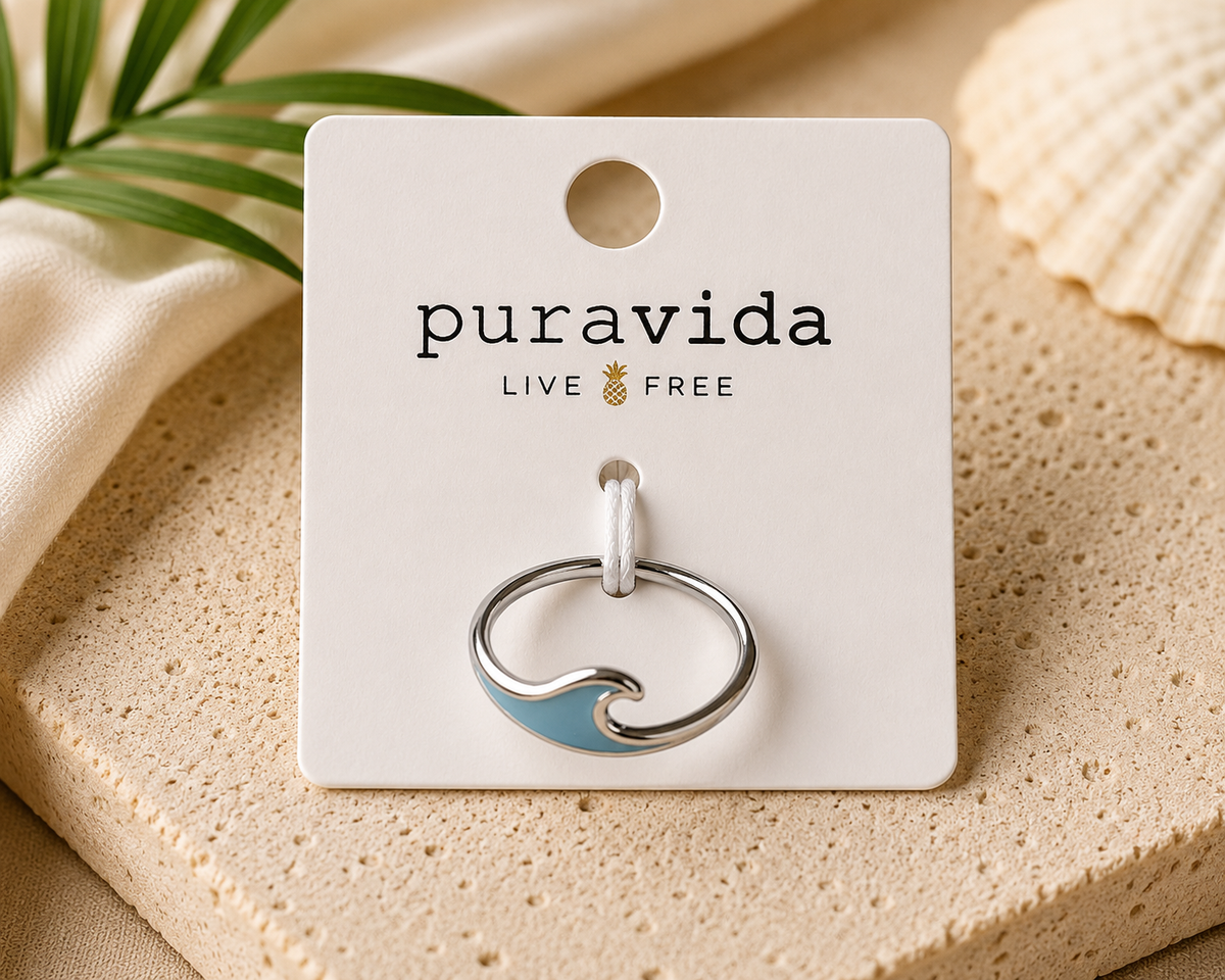 Authentic Pura Vida silver-tone band ring featuring a light blue enamel wave design, displayed new on the original branded Pura Vida card.