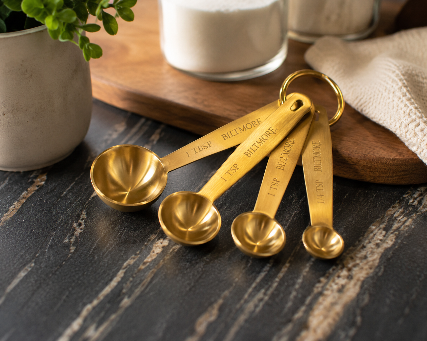Biltmore gold-tone measuring spoon set featuring four metal measuring spoons on a storage ring, designed for baking, cooking, and kitchen organization.