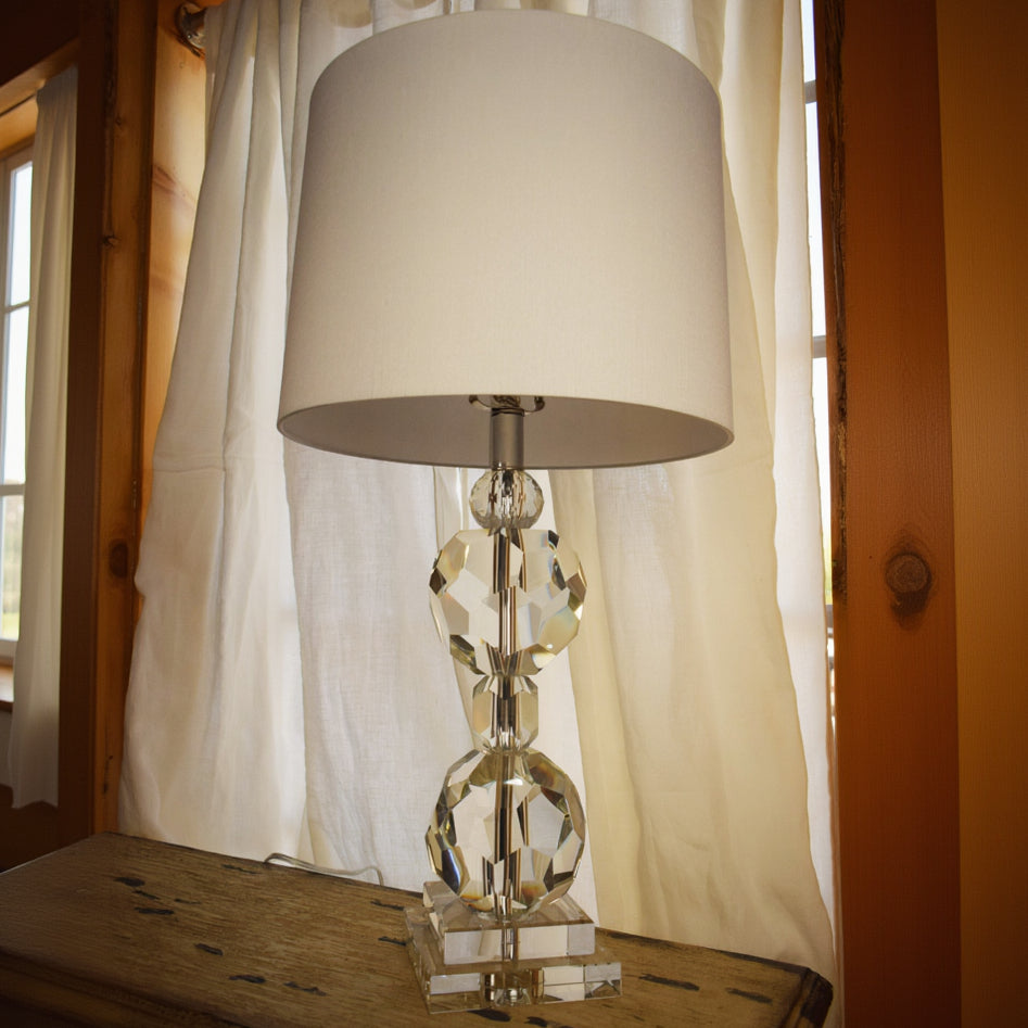 A unique 4 Tiered Stacked Crystal Ball Lamp with a crisp white fabric shade, showcasing a series of stacked crystal balls that provide a soft, ambient glow. 