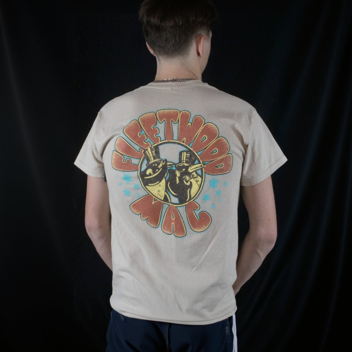 The off-white Fleetwood Mac Graphic T-shirt is available in a men's Medium size and features two penguins wearing top hats on the front and back.
