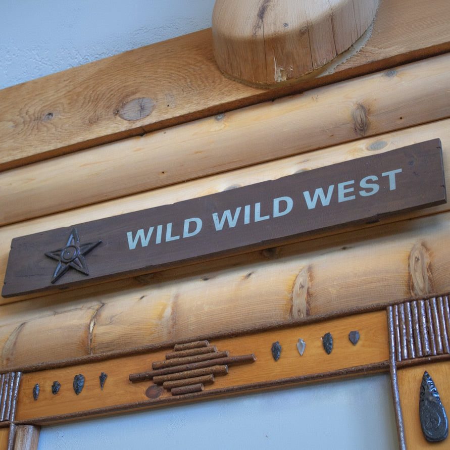 Wooden sign with 'WILD WILD WEST' text 
