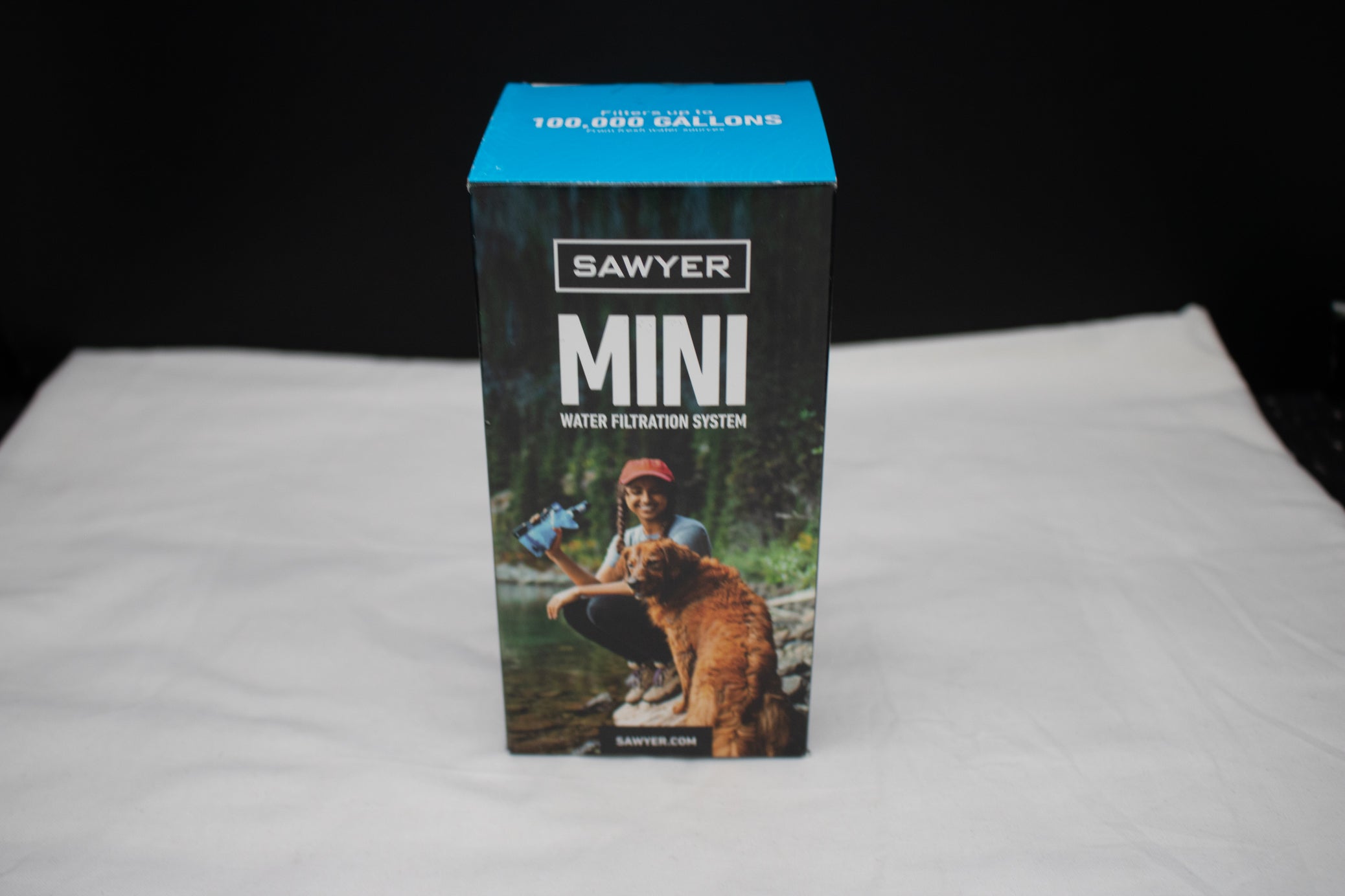 Sawyer MINI portable water filtration system in original retail packaging, capable of filtering up to 100,000 gallons of freshwater for hiking, camping, backpacking, emergency preparedness, and survival use.