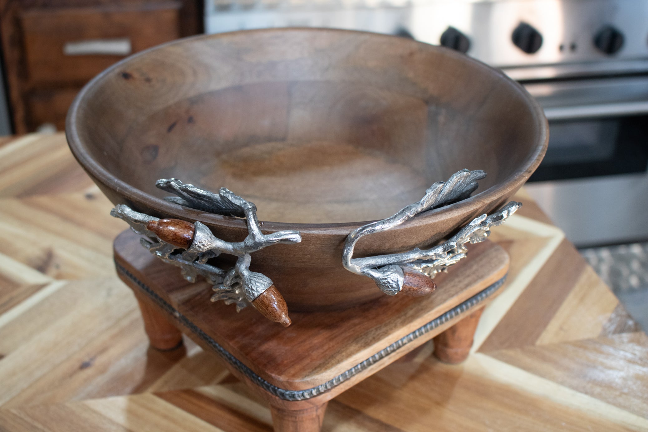 large handcrafted wooden bowl with decorative silver acorn and oak leaf branch handles filled with fruit rustic harvest collection decor