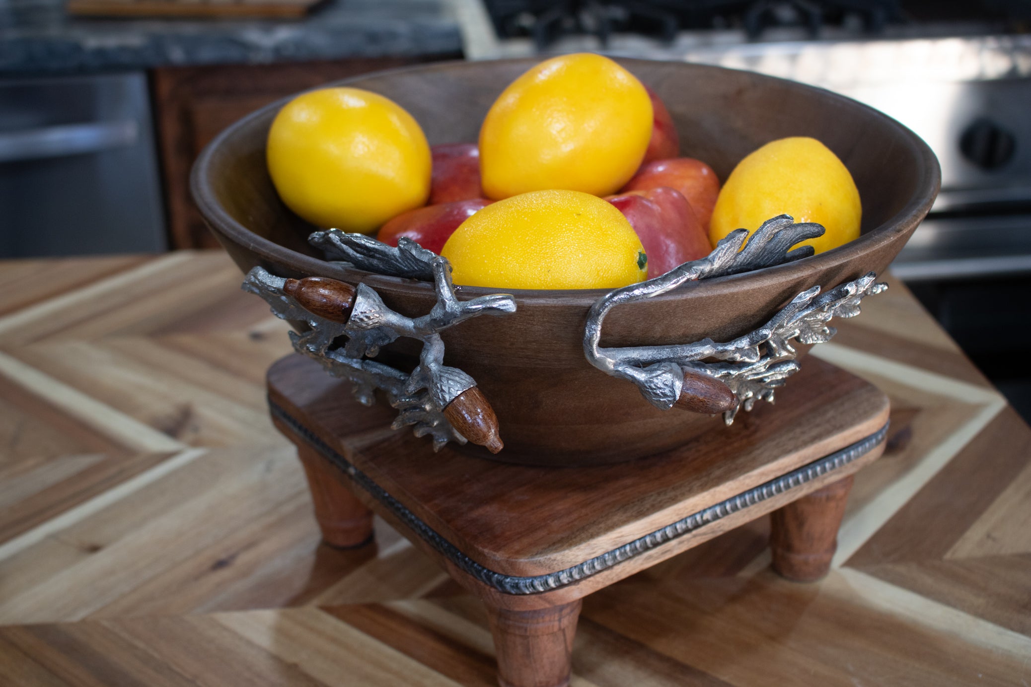 large handcrafted wooden bowl with decorative silver acorn and oak leaf branch handles filled with fruit rustic harvest collection decor