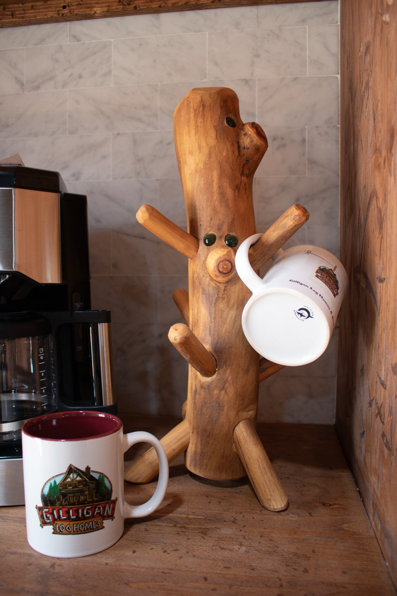 handcrafted rustic wooden mug holder with natural log style design and multiple peg arms displayed on countertop