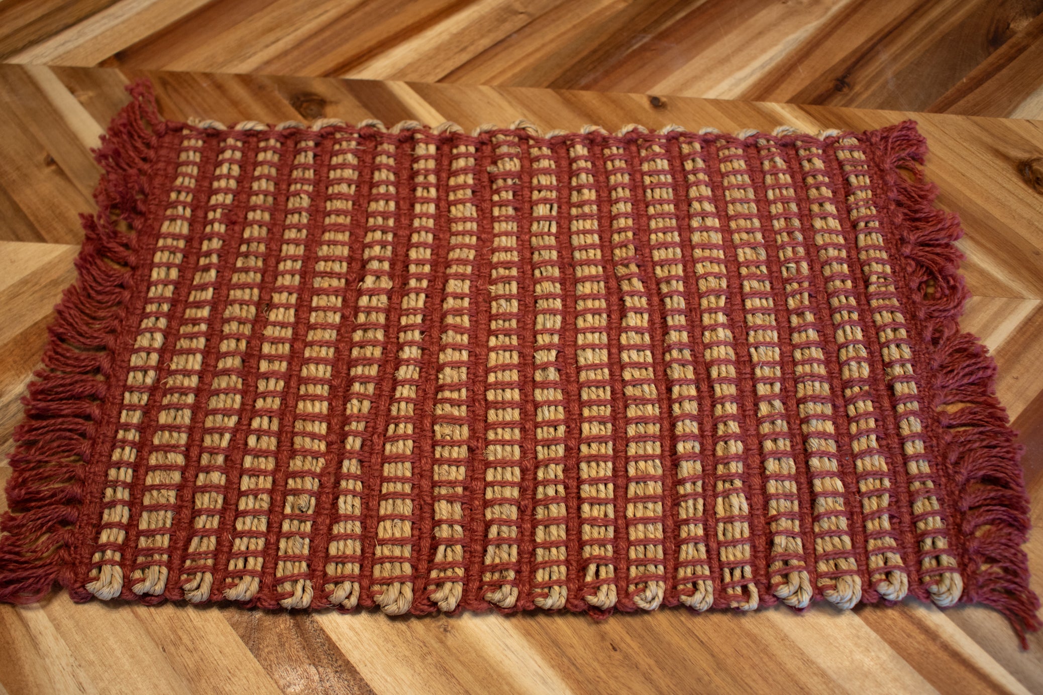 New set of seven handwoven rustic placemats featuring red and natural woven fibers with decorative fringe edges for farmhouse, cabin, and lodge-style dining tables.